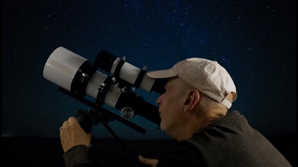 Wall Mural - a man stargazing through a telescope on a clear night