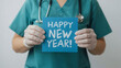© Anuyj - A nurse holding a blue paper and HAPPY NEW YEAR written on it. Celebrate the new year with nurses. Happy New Year for health care, wellness, and creative medical concepts.