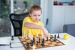 © Volodymyr - Child with chess at home. Boy studying strategy on chessboard. Cute kid playing thoughtful chess game. Schoolchild concentrating on chess figures. Teen learning logic through chess.