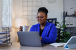 © David - African American business woman, A female secretary work on laptop Sitting at a Desk, reports to the workplace in the office, uses a computer