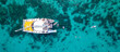 © zephyr_p - Aerial top view of sailing catamaran anchor over turquoise water with tourists swimming and paddle boarding at Racha Yai Island, A popular destination for summer vacation in Phuket, Thailand.