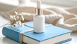 © Nanas - Skincare bottle with dropper on a blue book, next to a delicate white flower and soft cloth