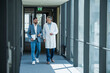 © Westend61 - Doctor and businessman discussing work while walking in office corridor