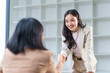 © amnaj - Smiling businesswomen shaking hands in a modern office, celebrating a successful meeting and solidifying a partnership agreement