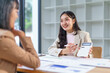 © amnaj - Two asian businesswomen using calculator and analyzing financial chart at office desk, discussing and working together on business plan