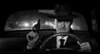 © stokkete - Detective with a gun in hand chasing criminals in his car, scene in 1950s American film noir style.