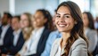 © NafiliaEmil - Happy young woman smiling at business seminar with diverse audience. Business and diversity themes. Detailed high quality image.