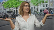 © Krakenimages.com - Woman wearing glasses shows open palms on street by bike parking and tree lined buildings; uncertainty.