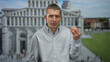 © Krakenimages.com - Man gesturing with expression in front of large cathedral backdrop on street scene outdoors, wearing striped shirt.