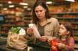 © Wojciech - Cost of living crisis experienced by mum looking a the shopping bill by the checkout with a concerned face expression.