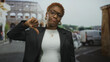 © Krakenimages.com - Young african american woman showing thumb down gesture outdoors in front of roman coliseum; disapproval dissent.