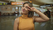 © Krakenimages.com - Woman with blonde hair makes victory sign in a brightly lit airport terminal departure lounge near gate c; playfulness.