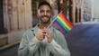 © Krakenimages.com - Young man holding lgbt flag with a smile on a city street embodies pride and diversity in an urban outdoor setting, highlighting a festive and inclusive atmosphere.