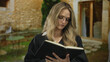© Krakenimages.com - Young blonde woman judge reading a book outdoors with stone building background in natural lighting environment.