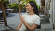 © Krakenimages.com - Young hispanic woman with mouth open looking to side on a busy city street wearing a white t shirt with visible shoulder; surprise discovery.