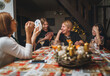 © Soloviova Liudmyla - Cheerfully warm home togetherness cozy scene of family playing cards together in home kitchen. Girls and boys smiling and laughing with moms. Holidays time spending and relations concept image.