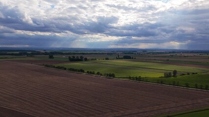 Wall Mural - sunlight shines through the clouds on the czech fields. farming in europe in hot summer. drone view