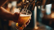 © Tichila - a hand pouring draft beer from a sleek black beer tap into a glass chalice. inside a bar.