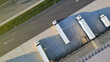 © wkproduction - Aerial view of a logistics hub with four trucks at loading docks, showcasing efficient freight transportation and organized warehouse operations, highlighting modern logistics infrastructure.