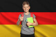 © New Africa - Little boy with backpack and stationery against flag of Germany. Language school