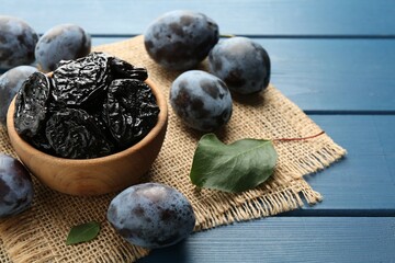 Wall Mural - Dried prunes and fresh plums on blue wooden table, closeup. Space for text