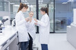 © charnsitr - Three scientists in lab coats engage in discussion in laboratory