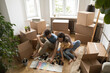 © fizkes - Parents with kid sitting on floor among boxes planning renovation