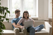 © fizkes - Happy young couple spend leisure time on couch with notebook