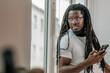 © carballo - young african man with dreadlocks and cell phone at the window