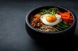 © Luminary Studio - Korean Bibimbap Featuring Fried Egg Served in a Stoneware Bowl, Dark Background