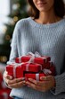 © Iryna - Young caucasian woman holding red christmas gifts near tree