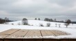 © anzuragfx - Wooden table dusted with snow overlooking a winter landscape with rolling hills and trees