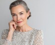 © Arwin - A mature woman with thoughtful expression, adorned in a glamorous gray beaded gown, radiates elegance and timeless beauty against a neutral backdrop.