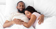 © Prostock-studio - Calm millennial african american female and male sleeping at night, hugging on bed in bedroom interior, free space. Relaxation and healthy sleep together at weekend, love and relationships, top view