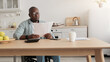 © Prostock-studio - African american freelancer typing on computer, paperwork with documents on table. Smiling mature disabled male in wheelchair in glasses works with accounting, paying taxes in kitchen interior