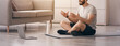 © Prostock-studio - Health and sports blog, advice on workout at home during covid-19. Smiling arabian bearded young man sits on mat, with bottle of water and looks at webcam on phone, explains to followers in room