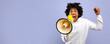 © Prostock-studio - Breaking news. Agitated black teenager shouting into megaphone over violet studio background. Emotional African American teen screaming with loudspeaker, making advertisement or announcement