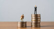 © Pixel Studio - Miniature figures stand on stacks of coins representing wealth inequality and financial disparity highlighting the gap between rich and poor in society and the economy