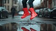 © muhammad - Red boots jumping in a puddle on a rainy day showing joy and freedom in an urban environment with cars blurred