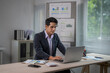 © Wasana - A man in a suit is sitting at a desk with a laptop in front of him