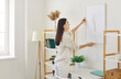 © Studio Romantic - Cheerful young woman arranging piece of art on wall, hanging picture on wall in her sunny, contemporary apartment, smiling and organizing, decorating her living space. Housing improvement concept