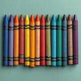 A row of colorful crayons arranged on a teal surface. The crayons show signs of use.