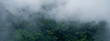 © Atthapon - banner background of the mountain landscape is veiled in a misty fog, with clouds drifting across the sky, while a solitary tree stands tall, embracing nature's serene beauty.