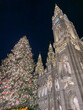 A christmas market with a large lit tree next to the city hall in vienna at night, concept of tourism, travel, holiday celebrations