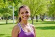 © DragonImages - Portrait of young adult Caucasian woman smiling outdoors in park, standing with relaxed posture, looking directly at camera, surrounded by green trees and grass