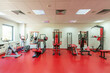© rilueda - Interior of a modern hotel gym with exercise equipment and  red floor