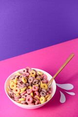 Wall Mural - Bowl with colorful sweet cereal rings and paper milk drops on pink table