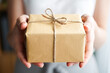 © Elena - Person is holding a brown box with a bow on it