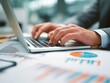 © lutforrahman - Preparing business financial report and document. Graphs and charts. Closeup of hands typing on laptop computer keyboard. Businessman working at desk in office.