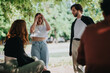 © qunica.com - A group of young people having a conversation outdoors, surrounded by lush greenery on a sunny day, creating a relaxed and natural atmosphere.